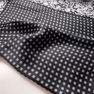 Detail of silk-like scarf featuring white floral borders and geometric square patterns