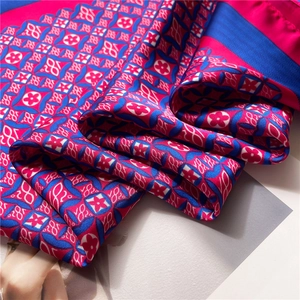 Macro detail of silk scarf showing fuchsia floral patterns and geometric grid textures