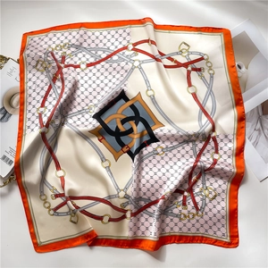 Détail d'un foulard en soie avec motifs de chaînes et bordure orange sur fond élégant