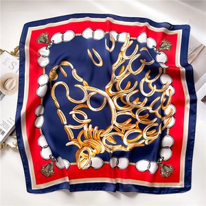 Detailed view of silk square scarf featuring gold chain patterns and red floral borders