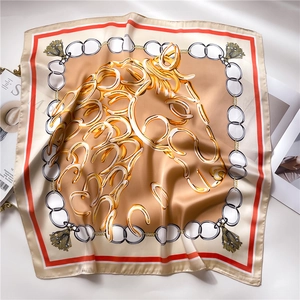 Detailed macro view showing the silky texture and horse chain print of the square scarf