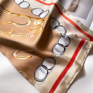 Detailed view of silky scarf with classic horseshoe and metal chain pattern in red and tan
