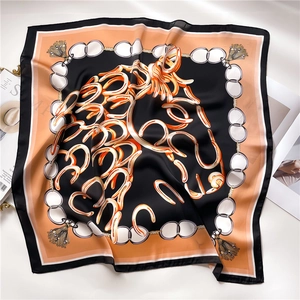 Close-up of silk square scarf featuring orange horse head and chain print with satin finish
