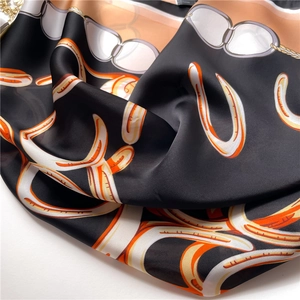 Close-up of silky black scarf with vintage orange chain print and satin texture