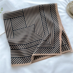 Classic black and yellow striped knit square scarf on a soft white fabric background