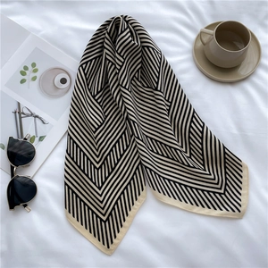 Detail of herringbone pattern silk scarf with elegant sunglasses and coffee lifestyle setup