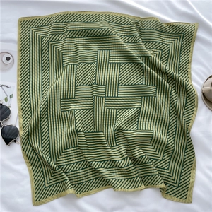 Close-up of green geometric striped silk scarf laid with lifestyle props for summer
