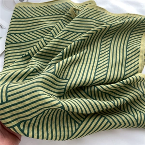 Detailed view of the green and yellow striped lightweight scarf with herringbone weave