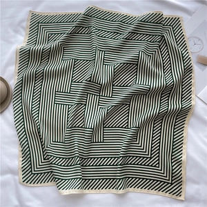 Macro detail of dark green and cream striped silk scarf with elegant satin finish texture