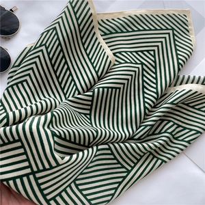 Detail view of the green and cream chevron stripe silk-like scarf with fine hemmed edges