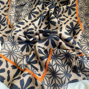 Detailed texture of beige cotton linen scarf with black chain patterns and orange border