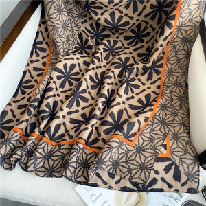 Detailed view of beige cotton linen scarf with black floral patterns on leather chair