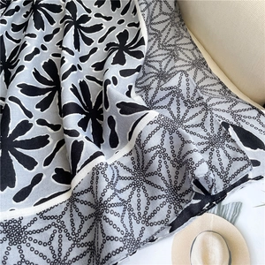 Close-up of floral print cotton-linen shawl draped over a beige fabric background