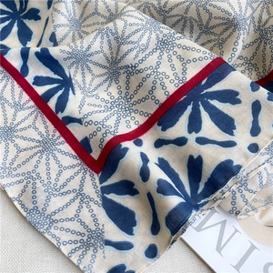 Detailed shot of beige floral cotton linen shawl with navy blue patterns and red edges