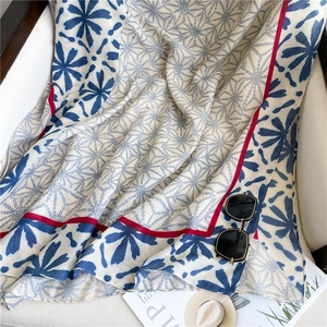 Detail of floral print cotton scarf with navy blue patterns and red edge accents