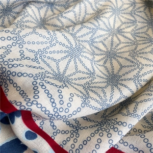 Macro shot of cotton linen scarf showing blue geometric patterns and red stitched edges