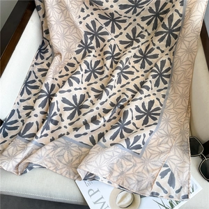 Close-up of elegant floral print cotton linen shawl with chain border on a soft chair