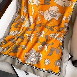 Vue détaillée d'une écharpe fleurie orange élégante avec des bordures géométriques