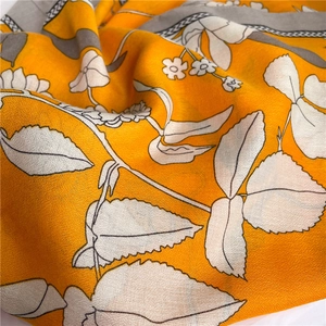 Détail d'écharpe en coton et lin avec motifs floraux orange et texture douce tissée