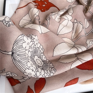 Gros plan d'une écharpe en coton et lin avec d'élégants motifs floraux rouges et soie