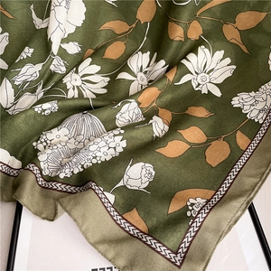 Détail de l'écharpe en coton et lin montrant l'imprimé floral vert foncé et sa texture