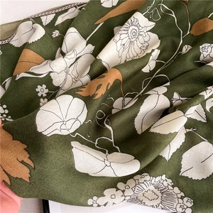 Vue détaillée d'un châle en coton et lin vert foncé avec un imprimé floral blanc élégant