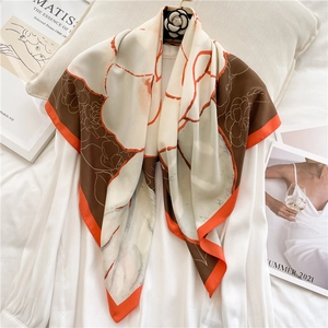 Detail of camellia print silk scarf draped over a shirt with elegant orange border