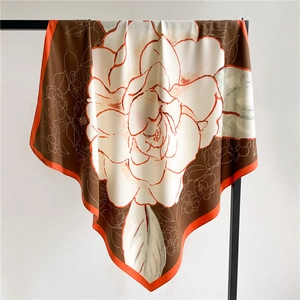 Detail of 90x90cm silk scarf showing camellia floral pattern and elegant orange border