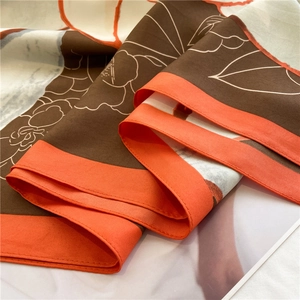 Detail of camellia silk scarf showing smooth twill texture and orange hand-rolled edge
