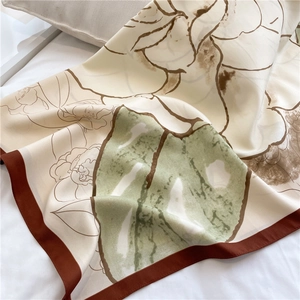 Detailed close-up of camellia floral print on a matte silk scarf with soft lighting