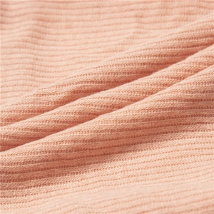 Macro detail of peach ribbed knit fabric showing soft texture and vertical stripe pattern