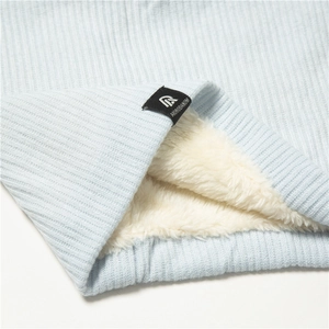 Close-up of light blue ribbed knit neck warmer with thick white fleece lining and logo tag