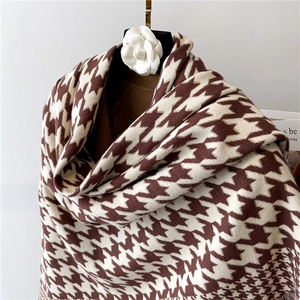 Detailed texture of brown houndstooth knit scarf on elegant flower hanger display