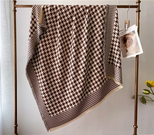 Detail of classic brown houndstooth oversized scarf with soft fringe edges and texture