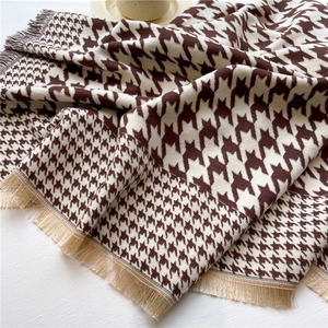 Close-up of patchwork houndstooth winter scarf with soft fringes and cashmere texture
