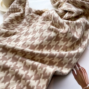 Macro detail of houndstooth scarf with soft fringe edges and thick knitted texture
