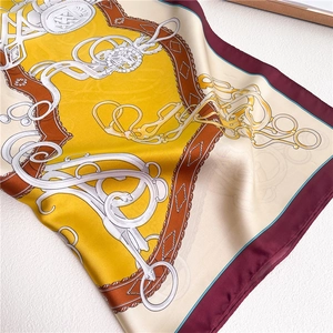 Detail of silk scarf with equestrian bits and chain patterns in yellow and burgundy