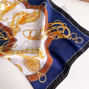 Close-up of silk square scarf featuring equestrian chain print and smooth satin texture