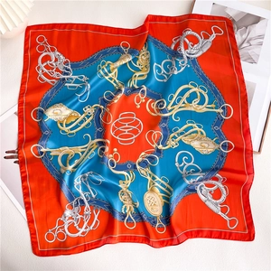 Detailed view of the luxury orange and blue silk scarf with equestrian patterns