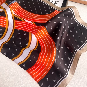 Macro detail of silky square scarf featuring geometric stripes and letter prints