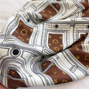 Close-up of silk scarf showing architectural prints and royal crown motifs on fabric