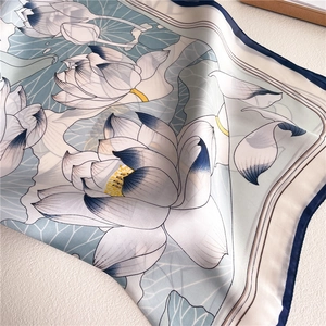 Elegant silk lotus scarf with blue floral prints and hand-rolled edges on white background