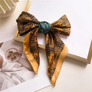 Close-up of silk scarf with mustard dragon patterns and black mesh on a golden frame