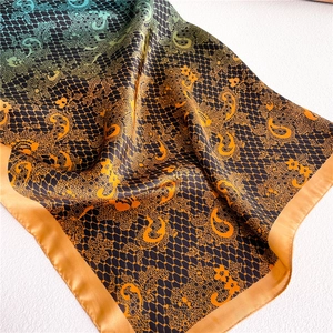 Detail of gradient silk scarf with lace pattern and paisley motifs in orange and teal
