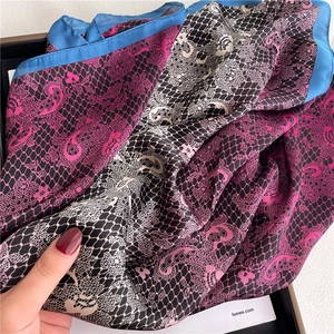 Detailed close-up of premium silk scarf featuring lace patterns and vibrant blue trim