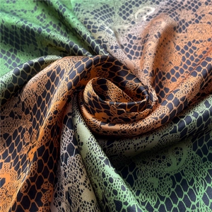 Close-up of luxury silk scarf with lace paisley patterns and green orange gradient satin
