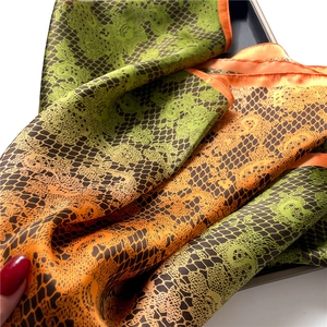 Detailed macro view of green and orange gradient silk scarf with black lace patterns