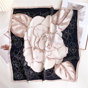 Macro detail of navy blue square silk scarf featuring camellia pattern and satin texture