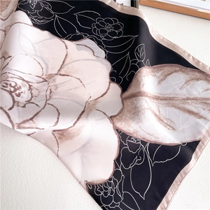 Detail of silk satin scarf featuring elegant camellia flower print and glossy texture