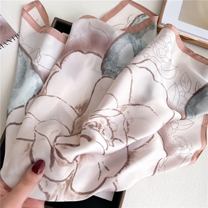 Close-up of silk square scarf showing camellia floral pattern and soft texture